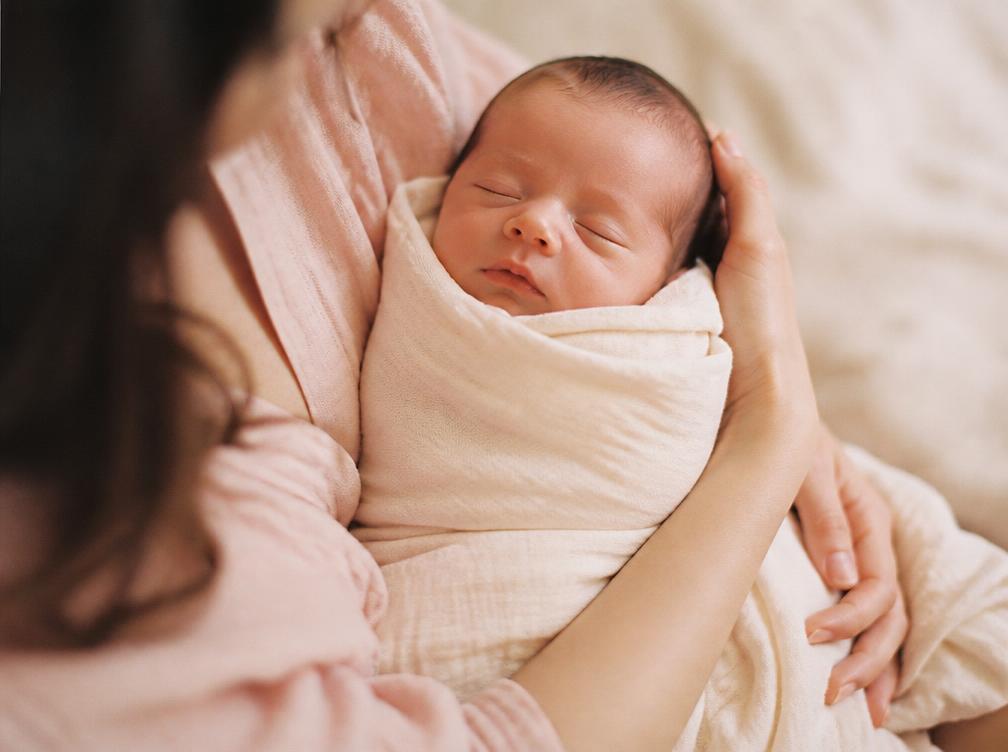 Nouveau-né emmailloté dans les bras d'un parent